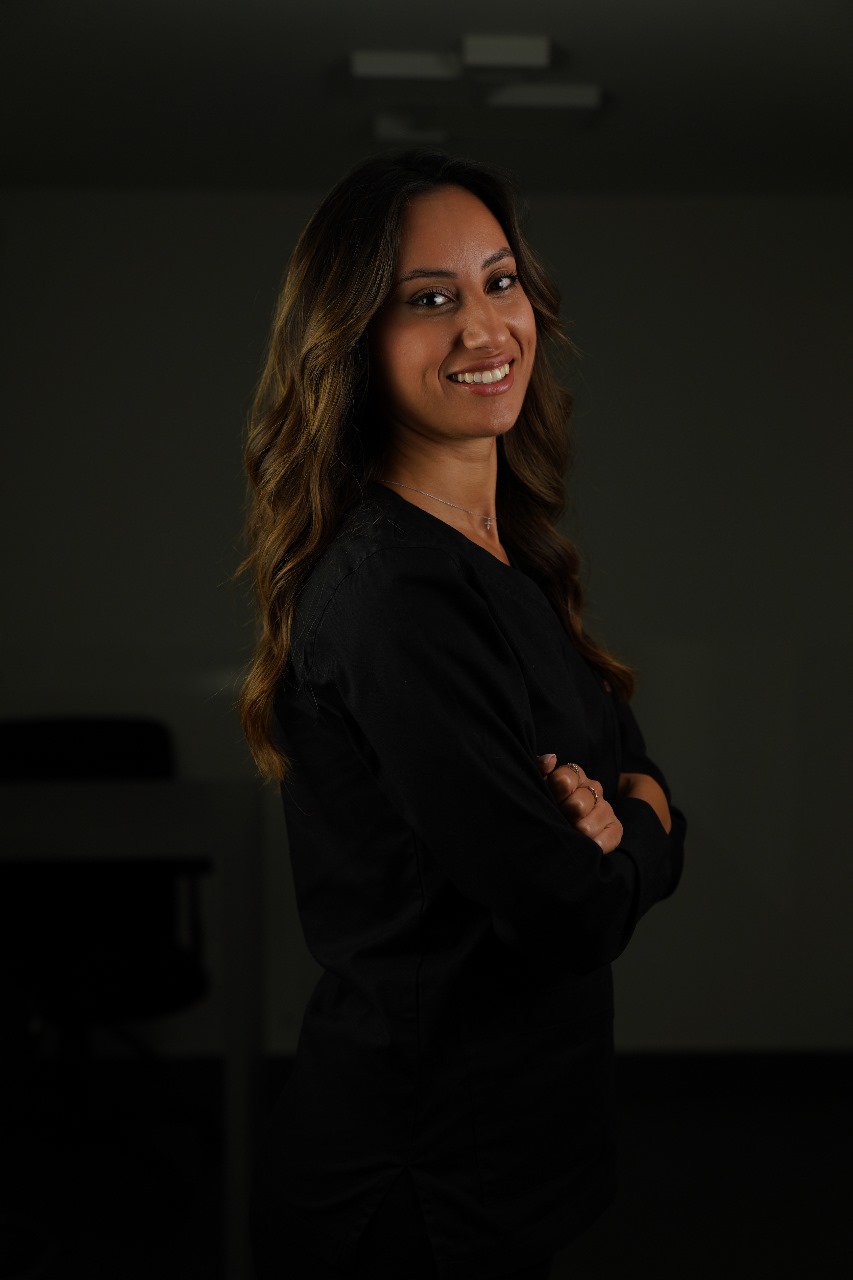 Portrait of a clinician in black scrubs, turned slightly toward camera